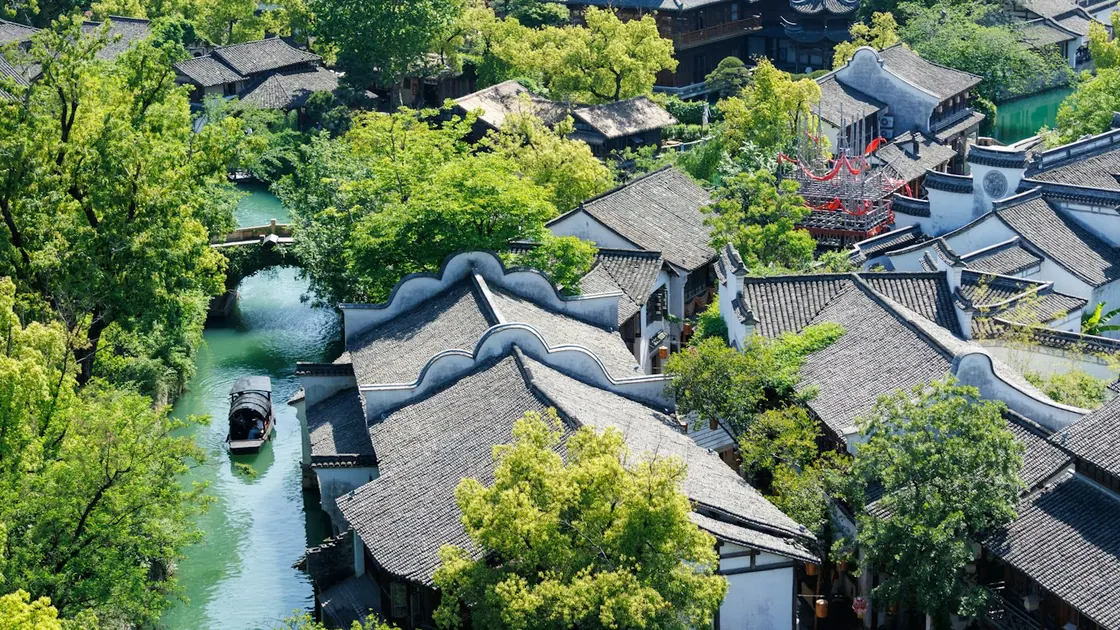 A narrow canal running between white-walled houses with grey tiled roofs, seen from above